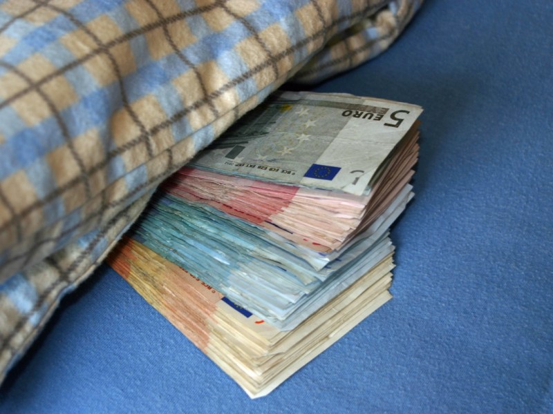 Geldscheine schauen unter einer Bettdecke hervor
