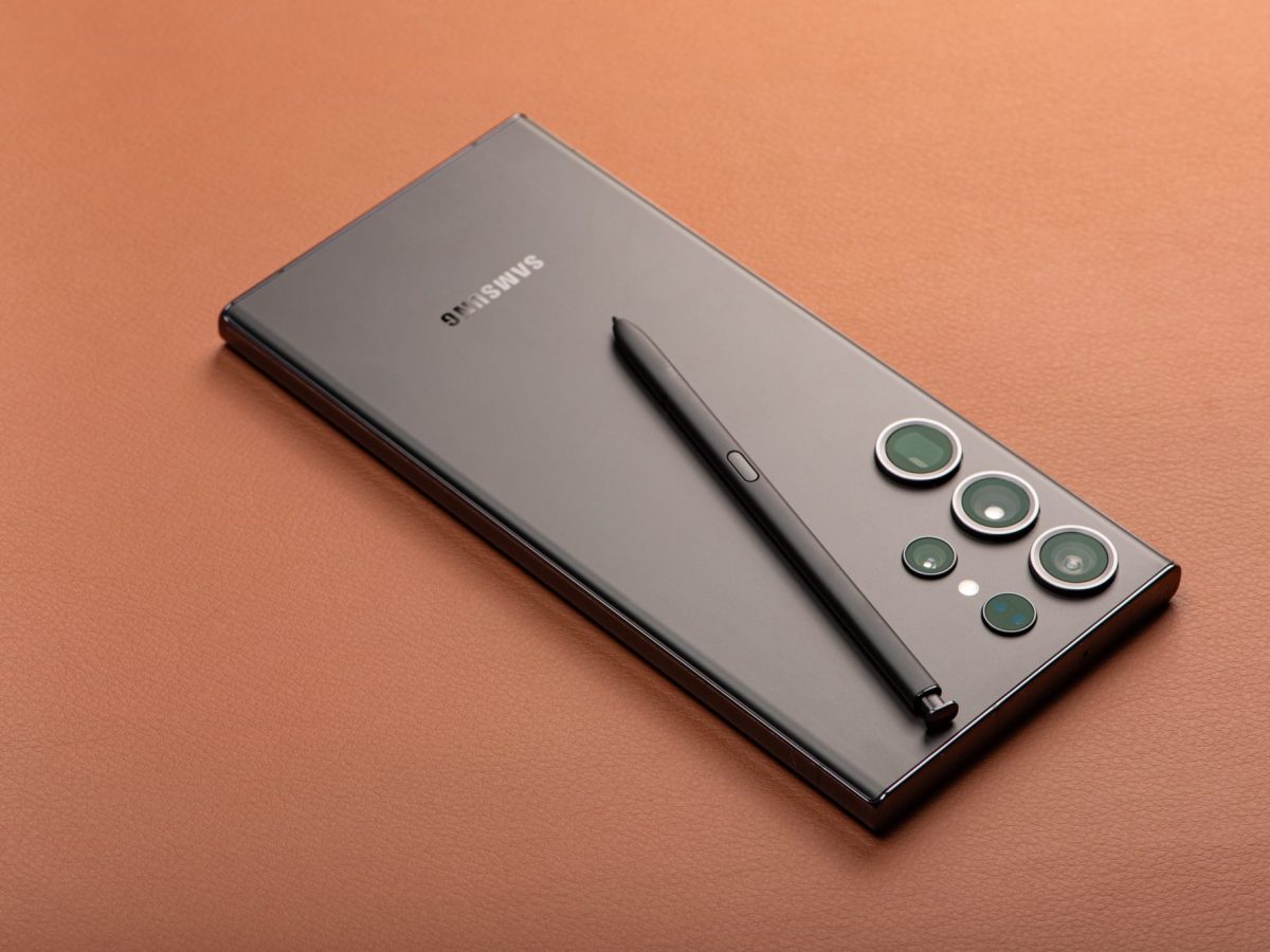 Ein graues Samsung Smartphone mit Stift liegt auf brauner Unterlage.