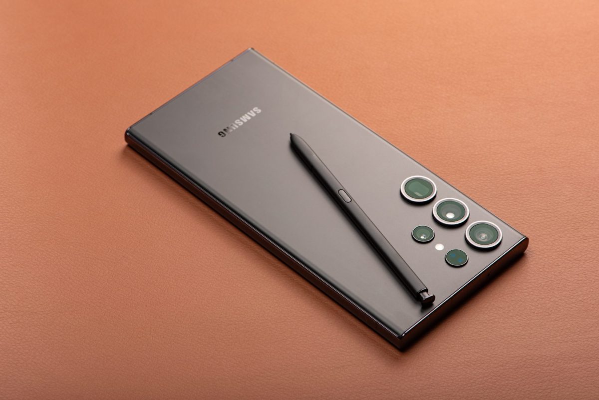 Ein graues Samsung Smartphone mit Stift liegt auf brauner Unterlage.