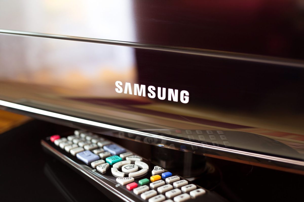 Samsung-Fernseher mit darunterliegender Fernbedienung auf einer braunen Oberfläche.