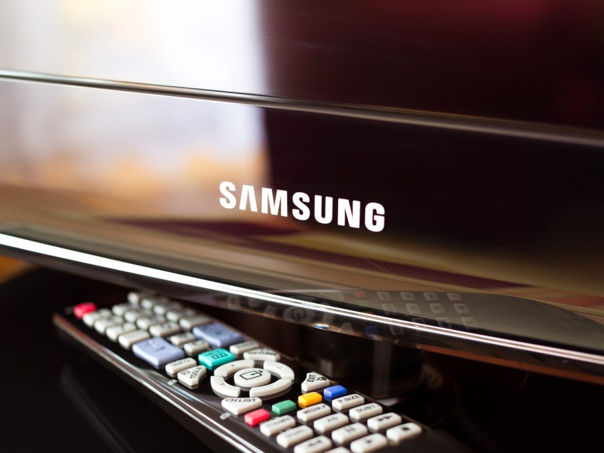 Samsung-Fernseher mit darunterliegender Fernbedienung auf einer braunen Oberfläche.