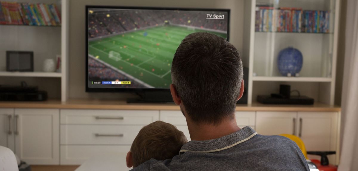 Vater und Sohn schauen Fernsehen über Satellit oder Kabel.