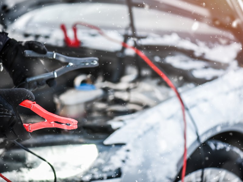 Starthilfekabel an einem verschneiten Auto
