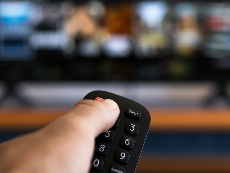 Hand schaltet Fernseher mit der Fernbedienung aus.
