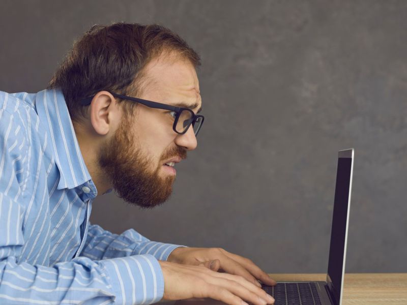 Mann schaut besorgt und erschrocken auf einen Laptop-Bildschirm.