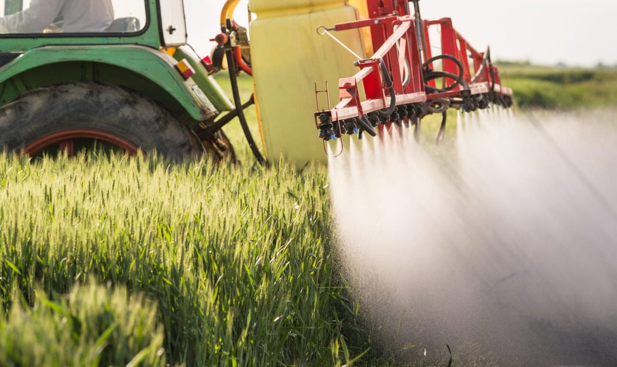 Ein Traktor besprüht ein Feld mit Pestiziden.