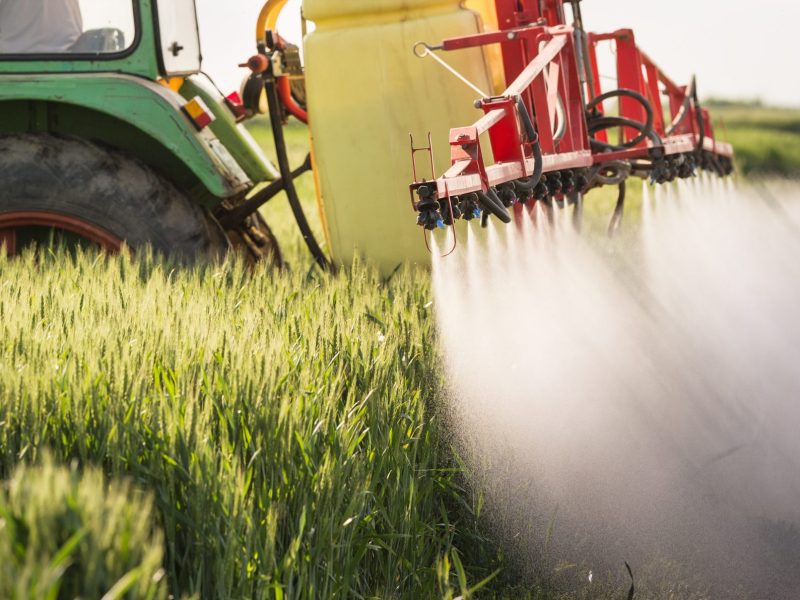 Ein Traktor besprüht ein Feld mit Pestiziden.