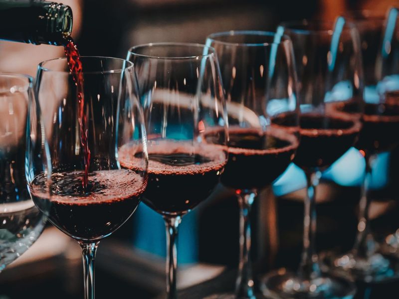 Mehrere Gläser Rotwein nebeneinander aufgereiht.