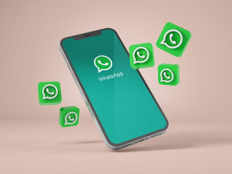 Mehrere WhatsApp Logos fliegen von einem Smartphone weg.