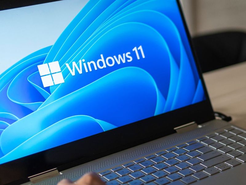 Person sitzt an einem Laptop mit Windows 11.