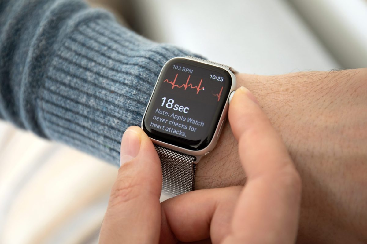 Apple Watch zeigt Herzfrequenz an, befestigt an einem Handgelenk, während zwei Finger die Uhr halten.