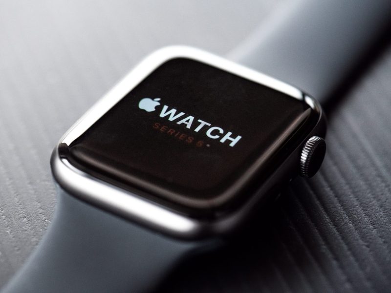 Apple Watch liegt auf einem dunklen Tisch und zeigt Logo an.