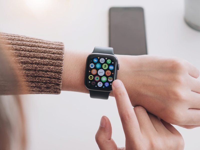 Apple Watch wird mit einem Finger angetippt, ist an einem Handgelenk befestigt.