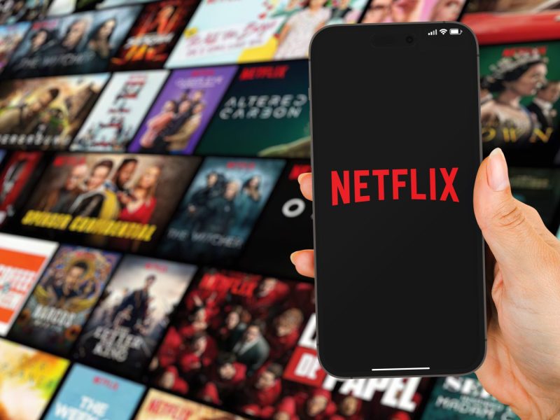 Eine Frau hält ein Smartphone mit Netflix.