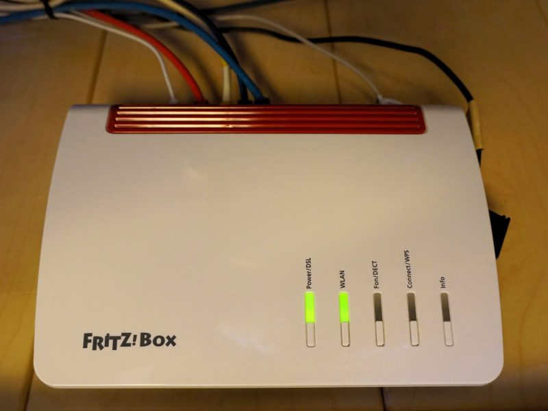 FritzBox-Router eingeschaltet auf einem dunklen Hintergrund.