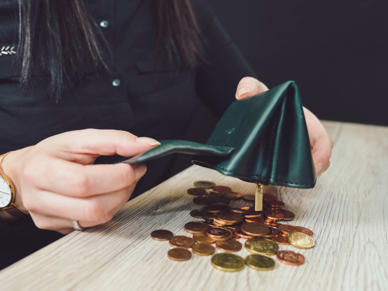 Person schüttet Münzen aus einem Portemonnaie.