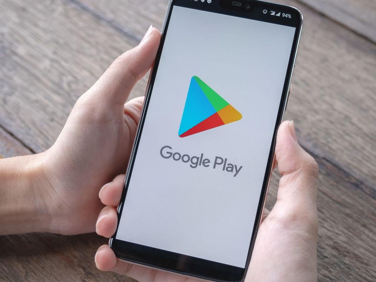 Person hält Handy mit dem Google Play Store auf dem Bildschirm in der Hand.