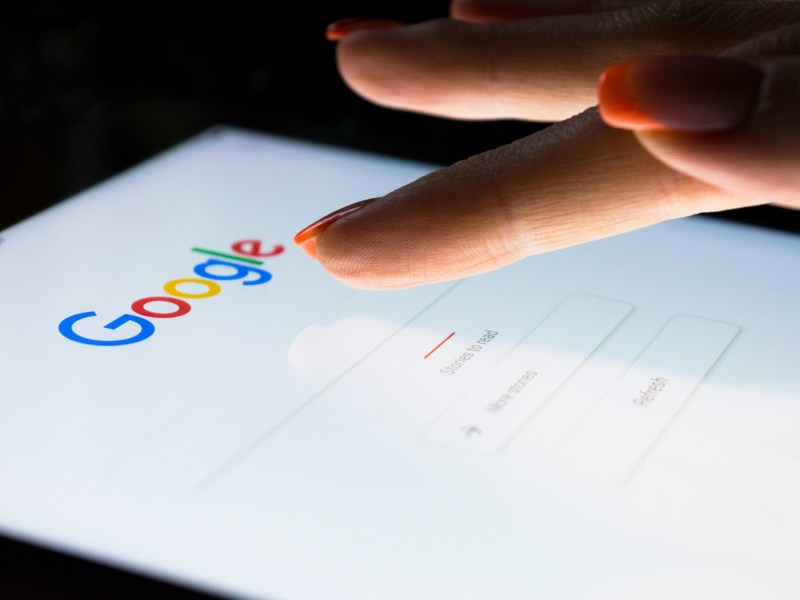 Person tippt mit dem Finger auf das Google-Suchfeld