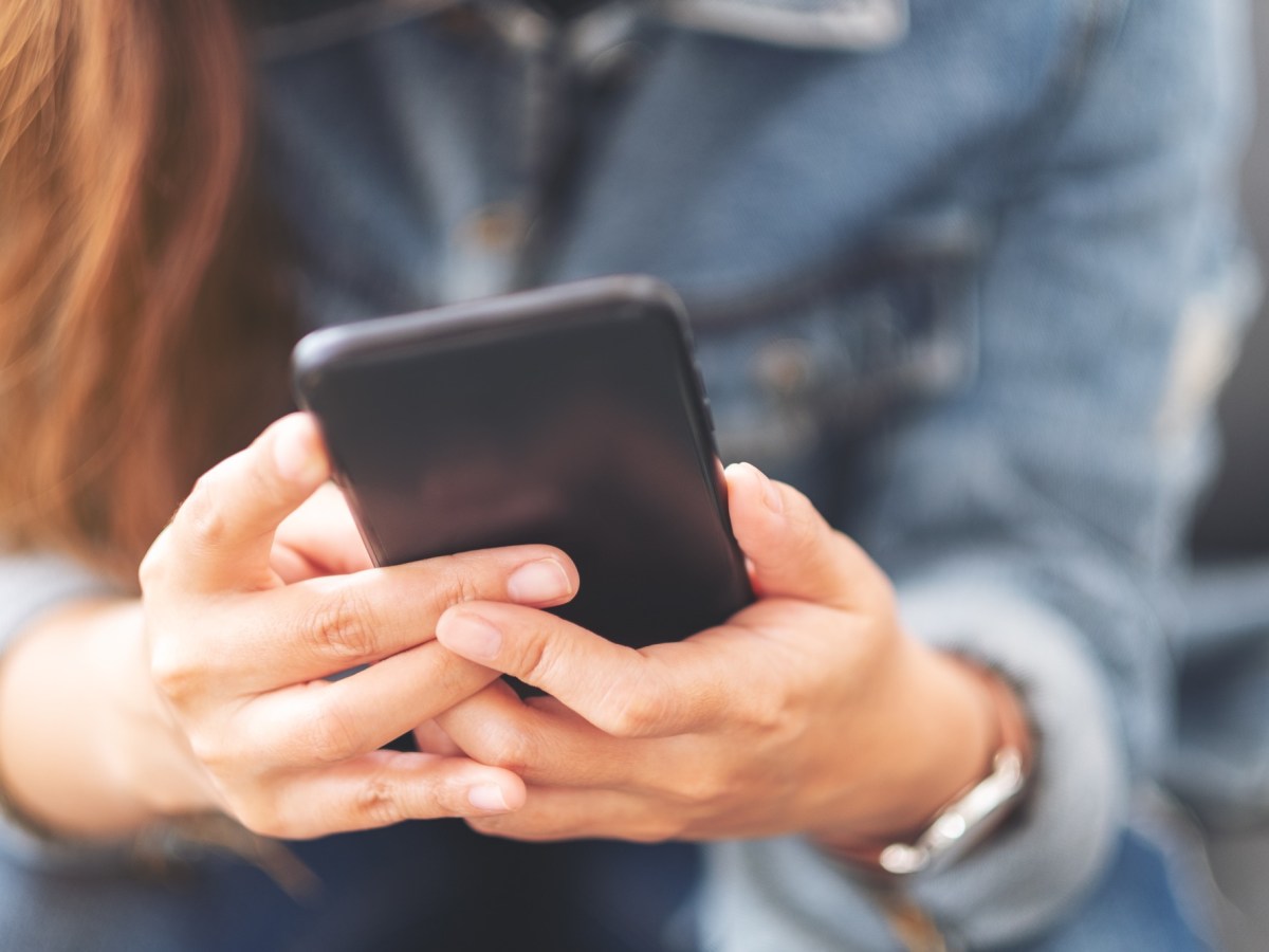 Eine Frau hält ein Handy in beiden Händen