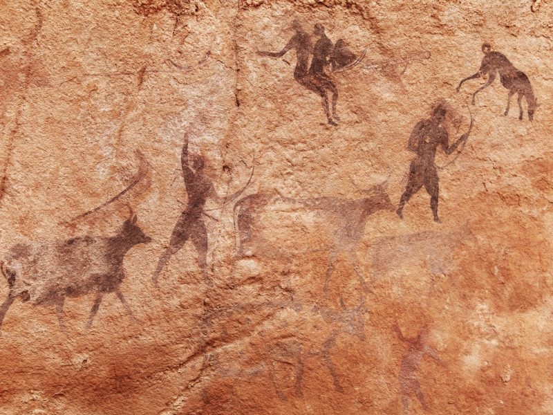 Eine prähistorische Höhlenmalerei zeigt eine Jagdszene.