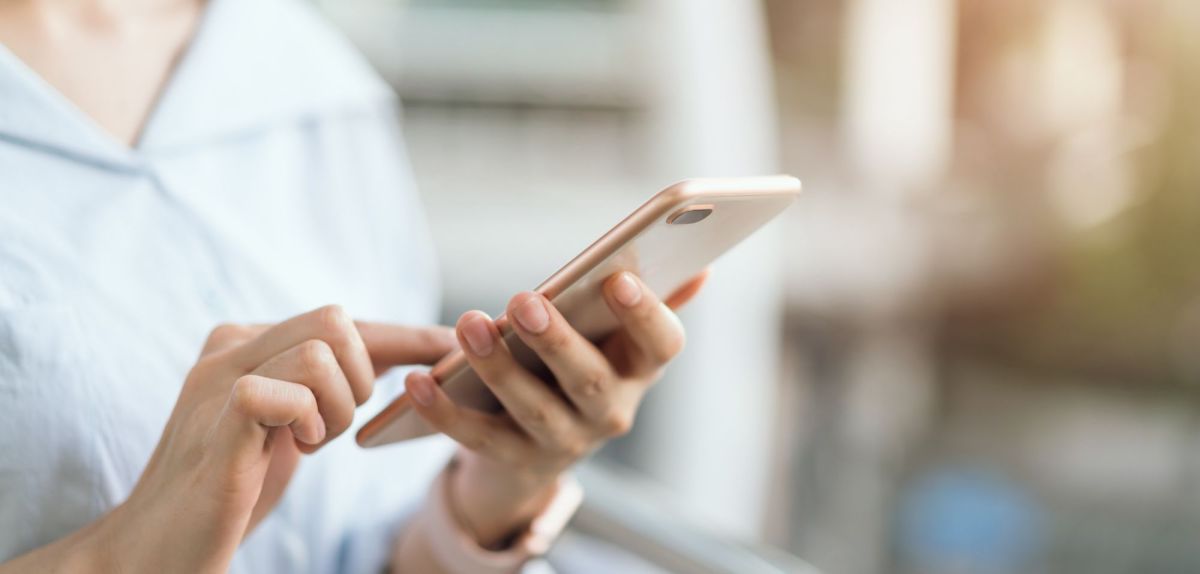 Frau hält ein Smartphone in der Hand.