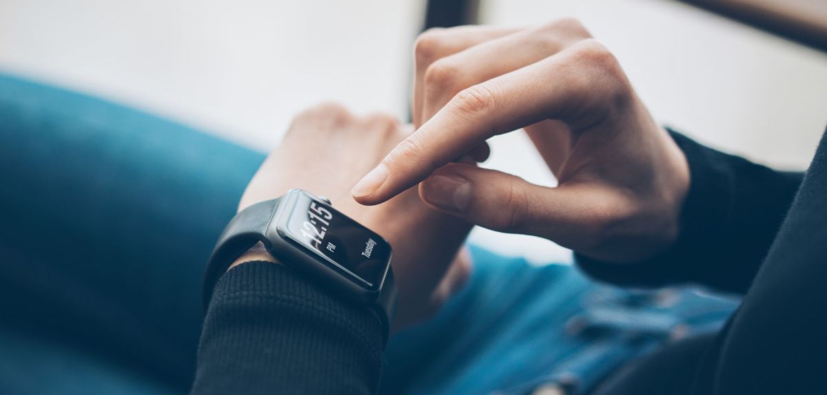 Person tippt auf einer Smartwatch an ihrem Handgelenk herum.