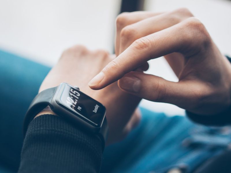Person tippt auf einer Smartwatch an ihrem Handgelenk herum.