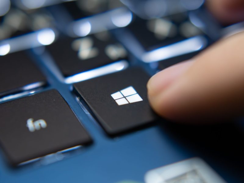 Finger zeigt auf Windows Taste an der Laptop-Tastatur.