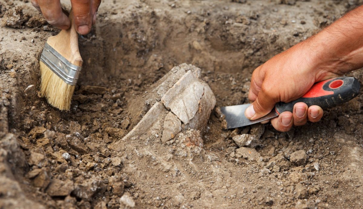 Eine archäologische Ausgrabung mit Spachtel und Pinsel.