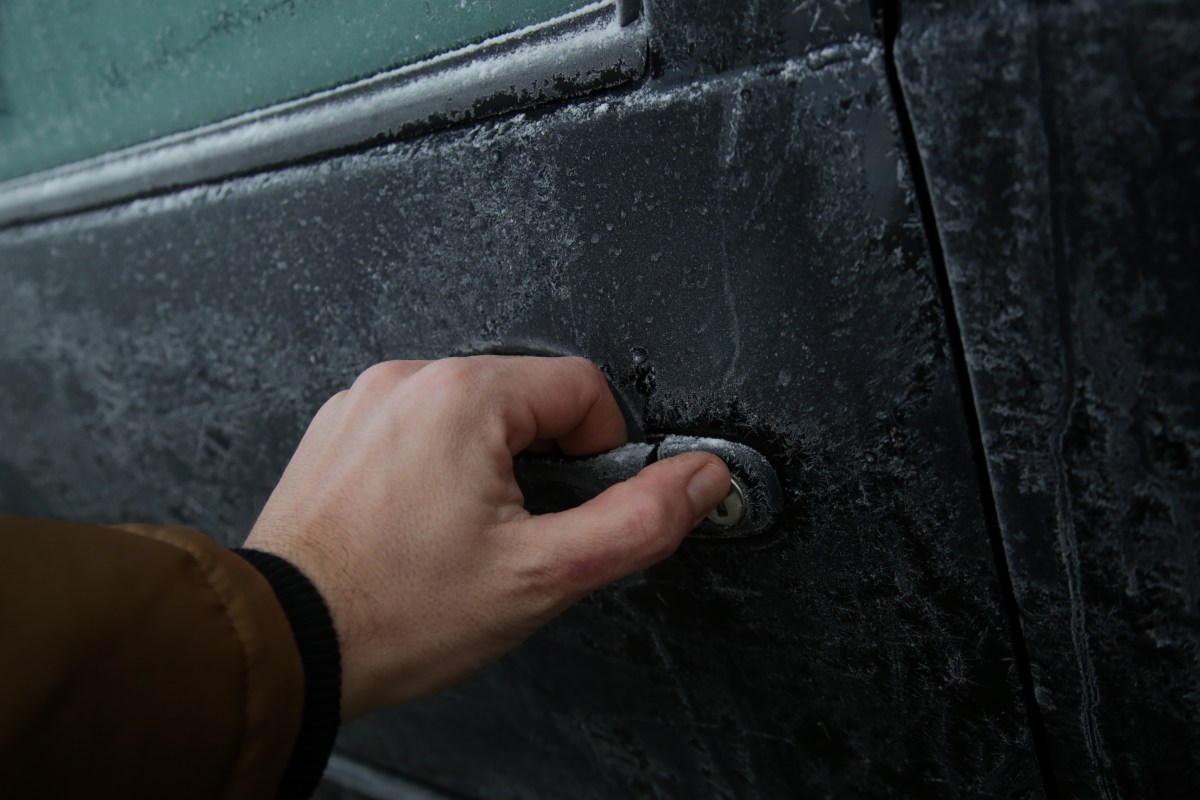 Person versucht, eine gefrorene Autotür zu öffnen