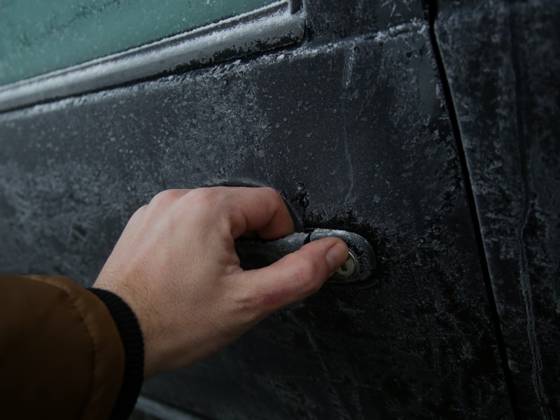 Person versucht, eine gefrorene Autotür zu öffnen