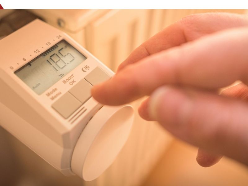 Finger tippt auf ein Heizkörperthermostat