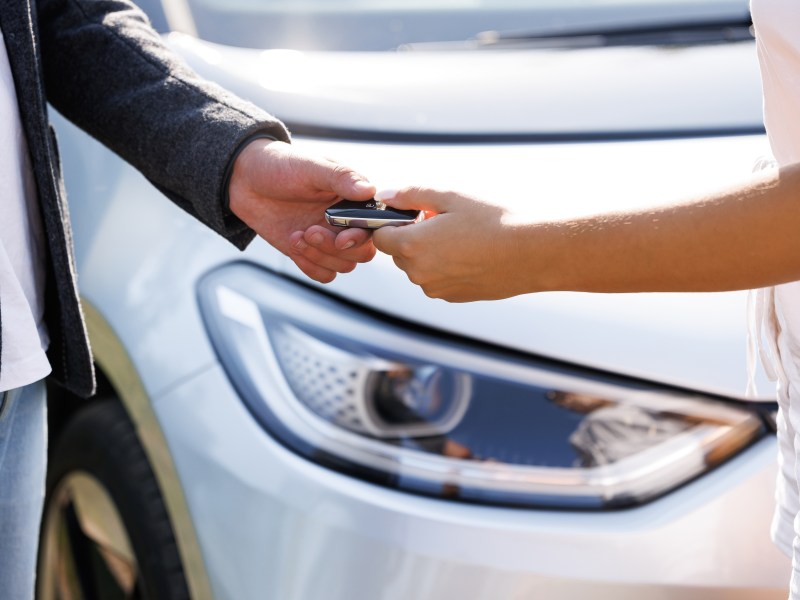 Person übergibt den Schlüssel eines Elektroautos