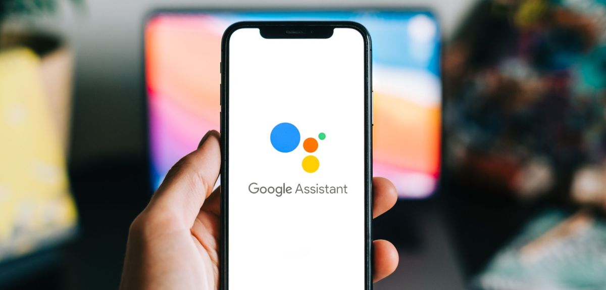 Person hält Handy mit Google Assistant in der Hand.