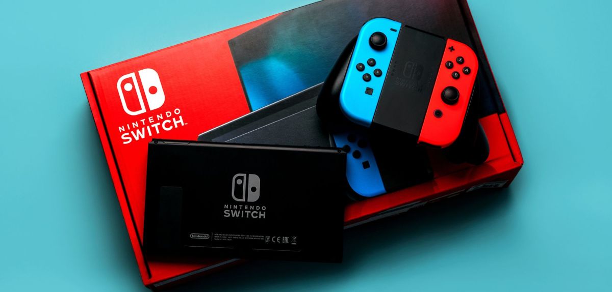 Eine Nintendo Switch mitsamt Verpackung auf blauem Untergrund.