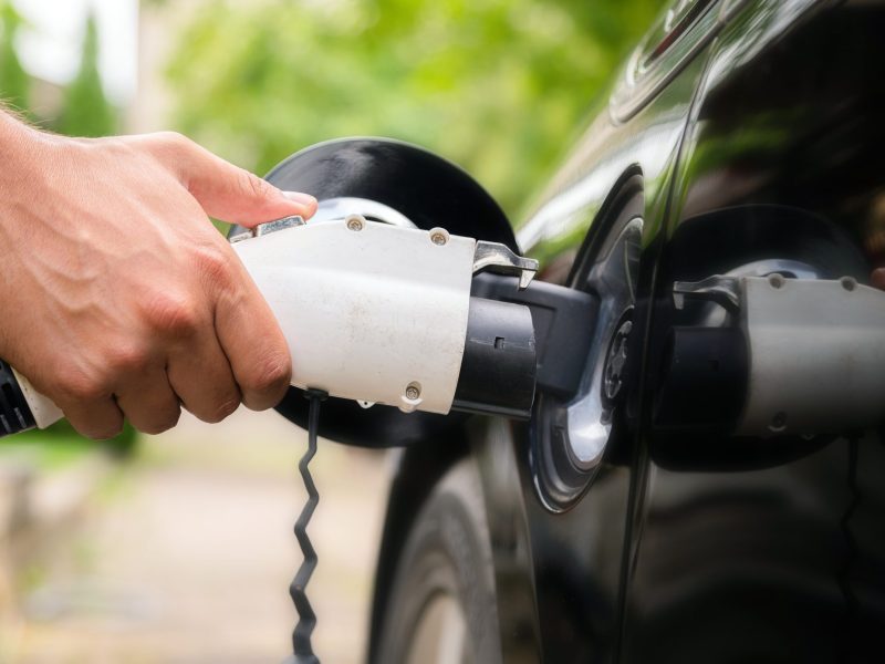 Ein Mann lädt sein schwarzes Elektroauto auf.