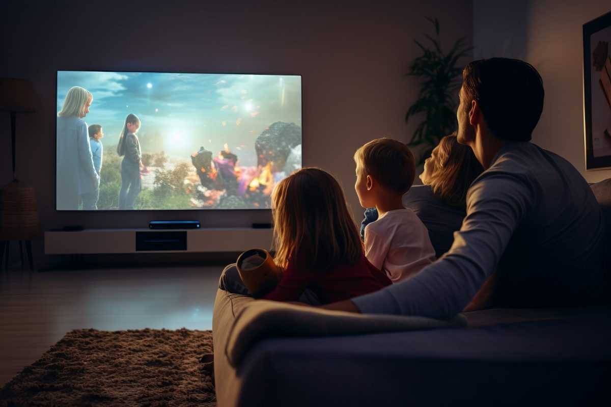 Ein Vater sitzt mit seinen drei Kindern vor dem Fernseher.