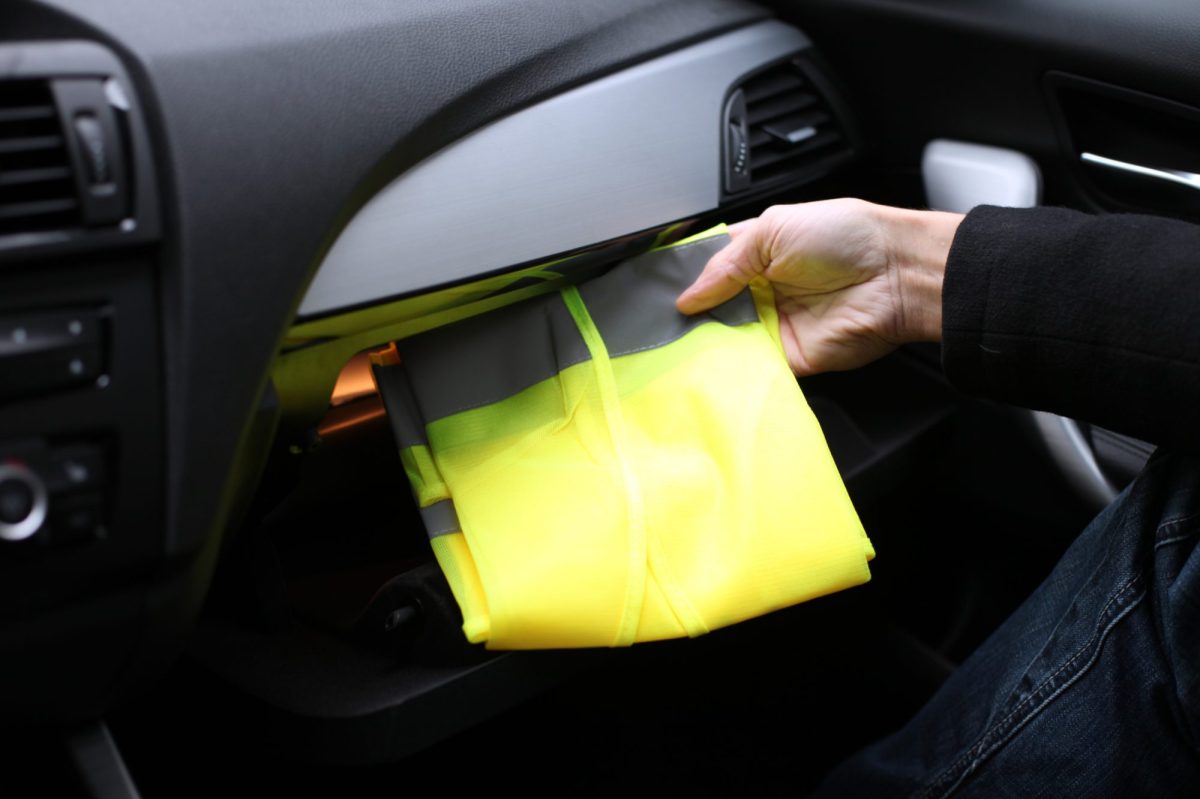 Person zieht eine Warnweste aus dem Handschuhfach ihres Autos.