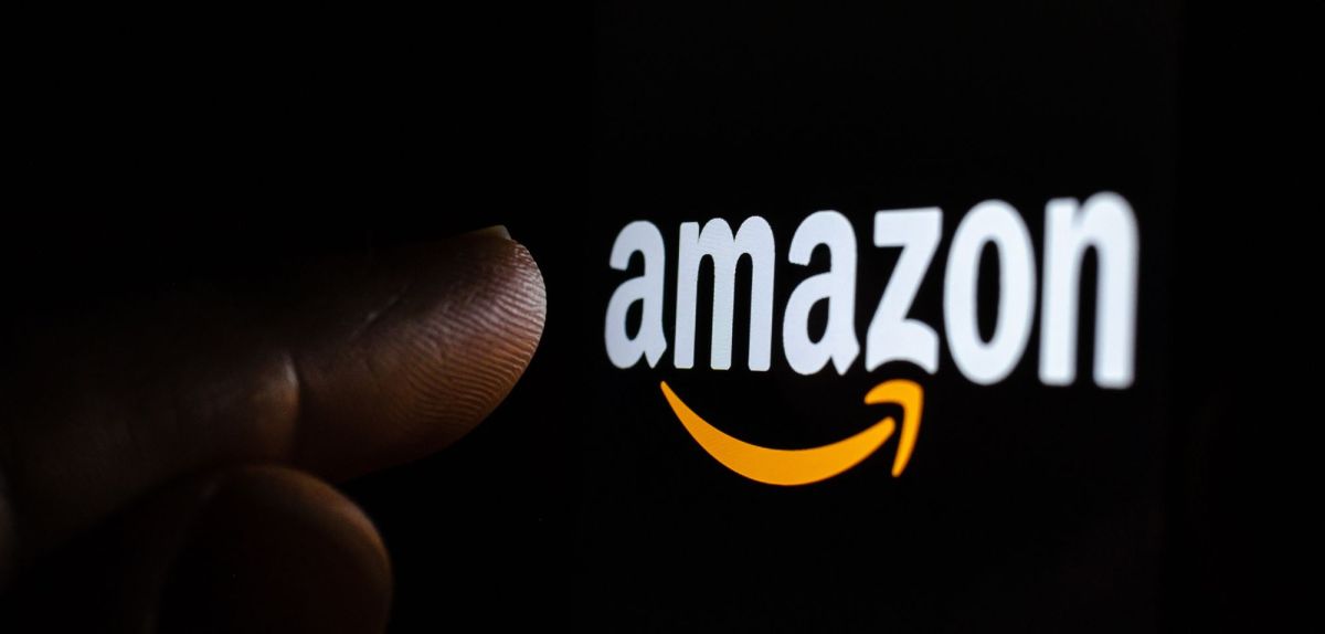 Finger zeigt auf das Amazon-Logo auf einem Bildschirm.