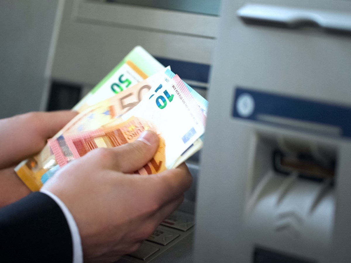 Mann hebt Bargeld am Geldautomaten ab