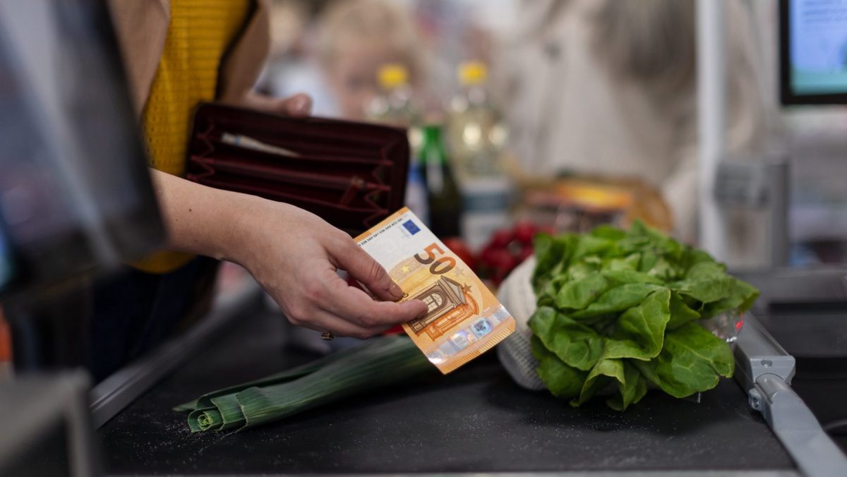 Frau bezahlt mit Bargeld an der Kasse