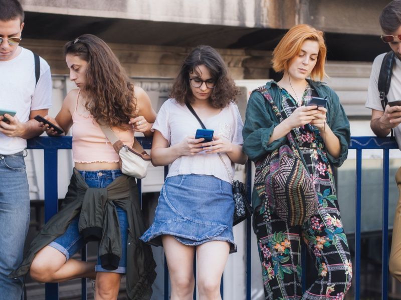 Eine Gruppe junger Menschen, die allesamt auf Smartphones schauen.