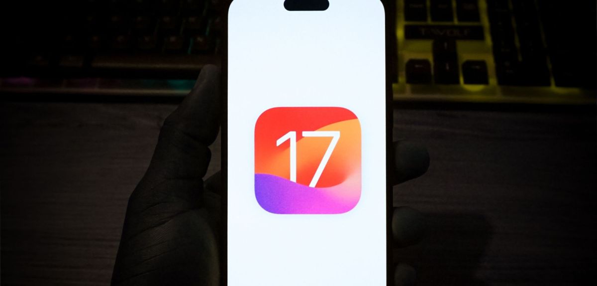 Person hält ein Handy mit einem Symbol für iOS 17 in der Hand.