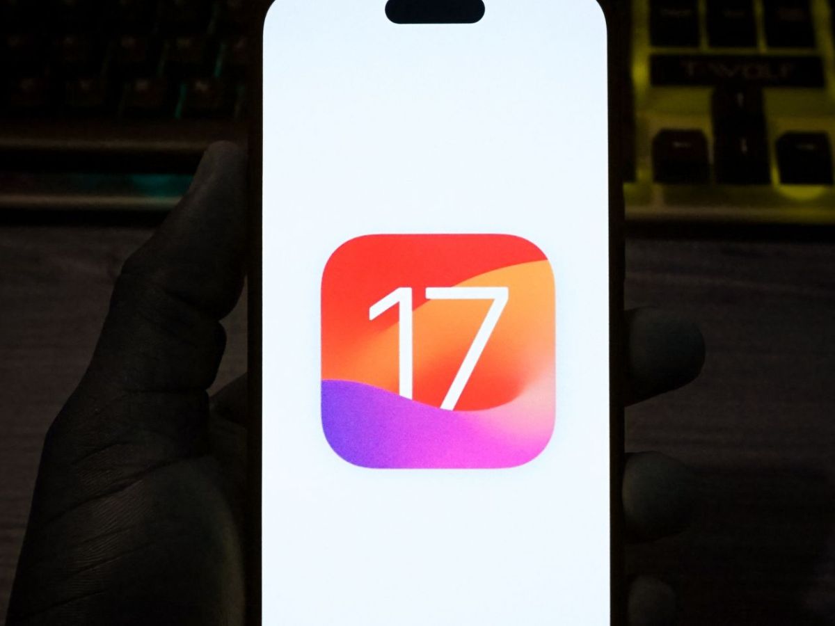 Person hält ein Handy mit einem Symbol für iOS 17 in der Hand.