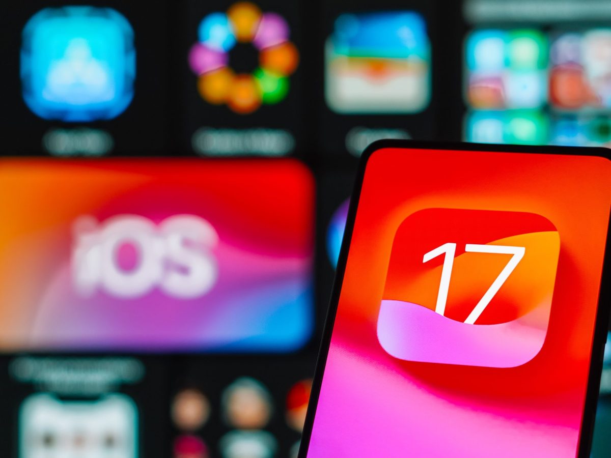 Smartphone-Bildschirm zeigt iOS 17-Logo an, vor Hintergrund weiterer Bildschirme.