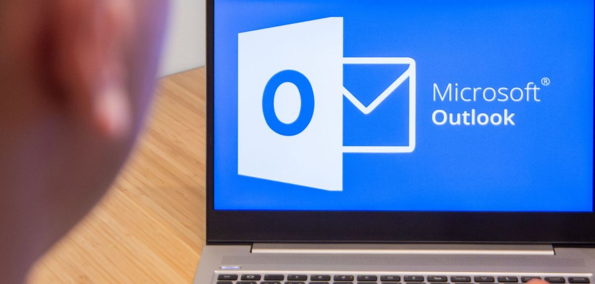 Mann sitzt vor dem Laptop mit Microsoft Outlook.