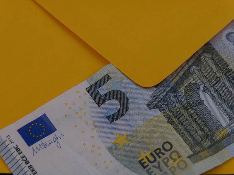 5-Euro-Schein vor einem gelben Briefumschlag