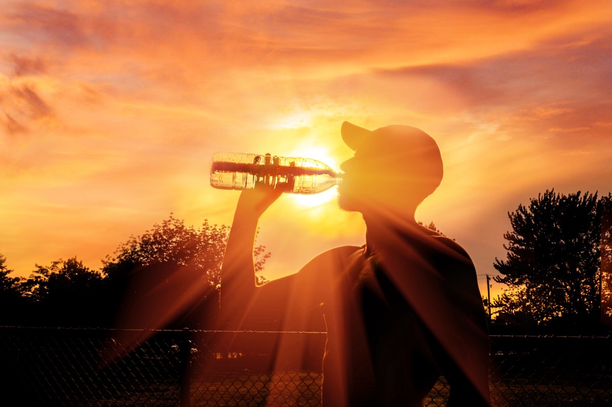 Mann trinkt Wasser vor Sonnenuntergang