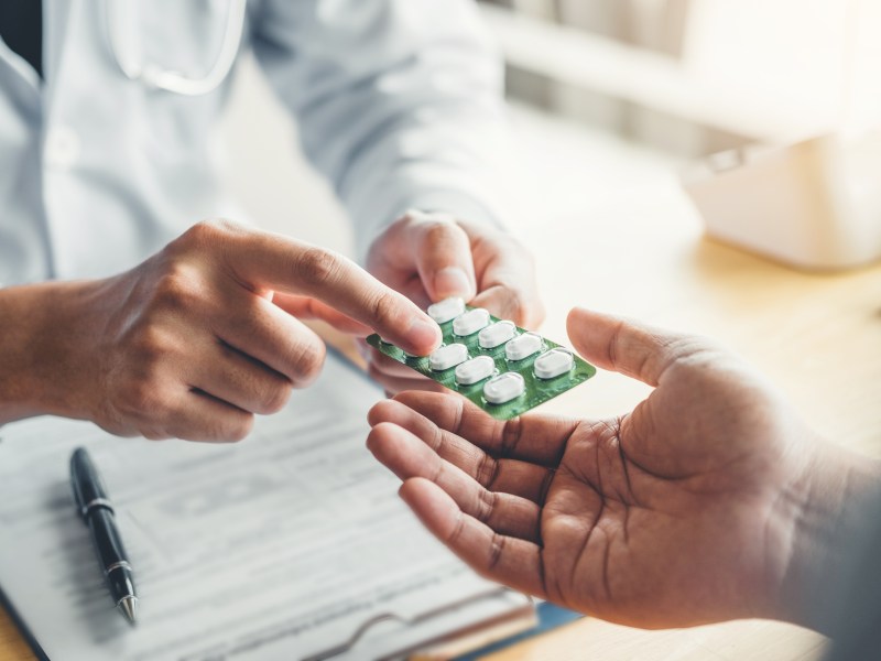 Person übergibt einer anderen eine Tabletten-Packung