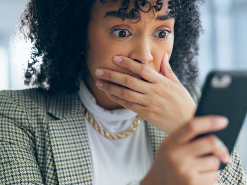 Frau blickt schockiert auf ihr Smartphone